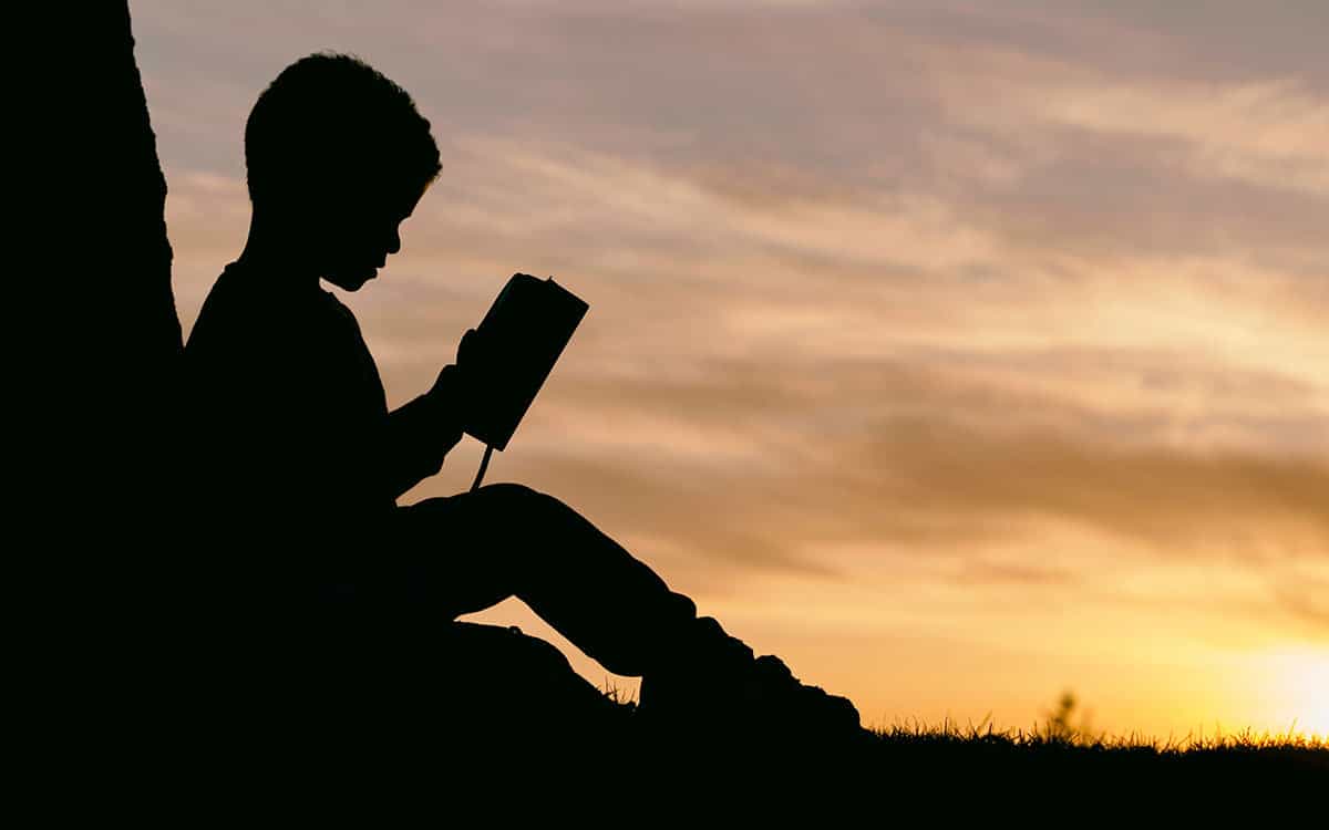 Child reading under a tree.